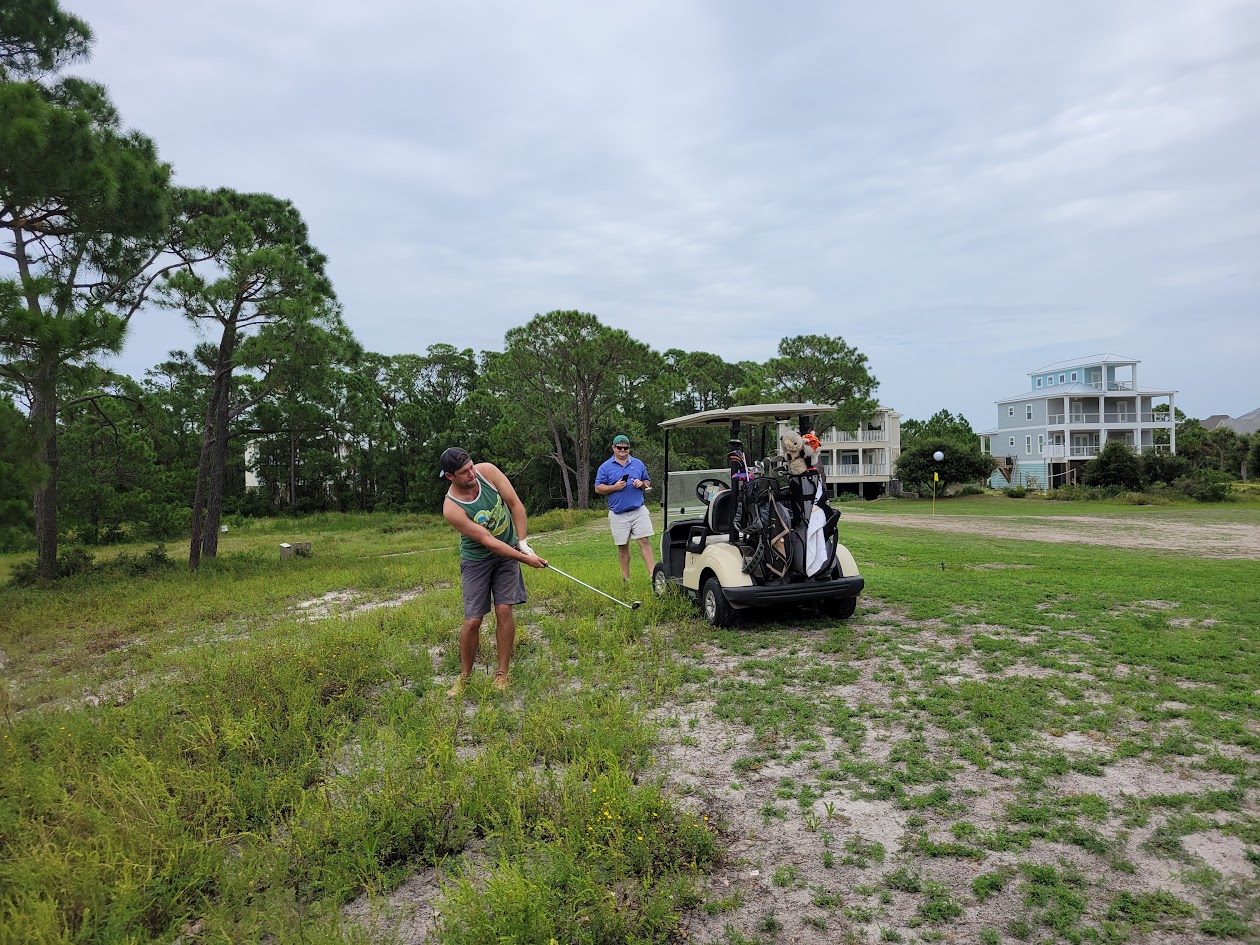 An HFFL owner playing a golf shot from deep rough beside a cart