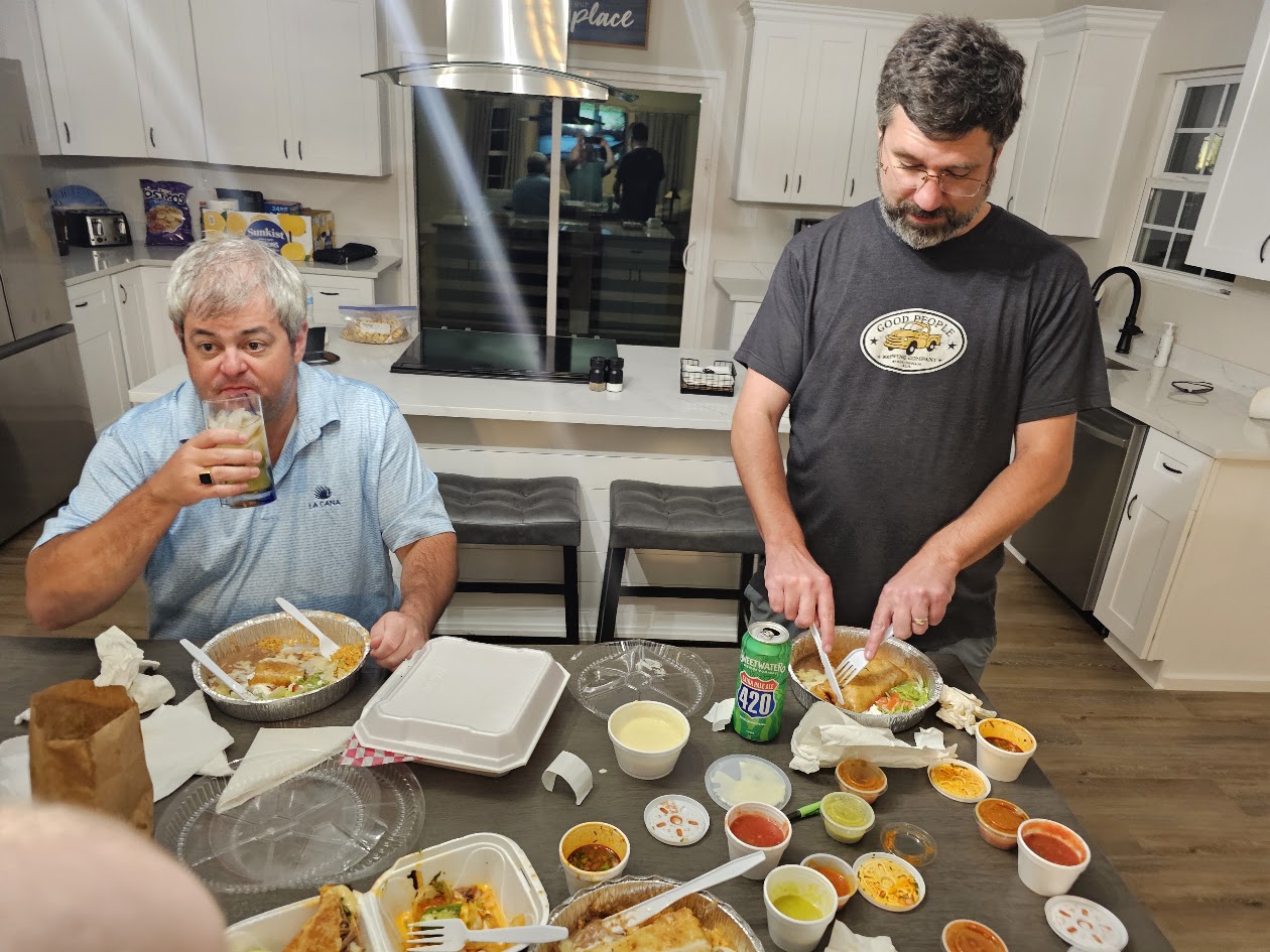 Two HFFL owners eating late-night takeout at a kitchen table